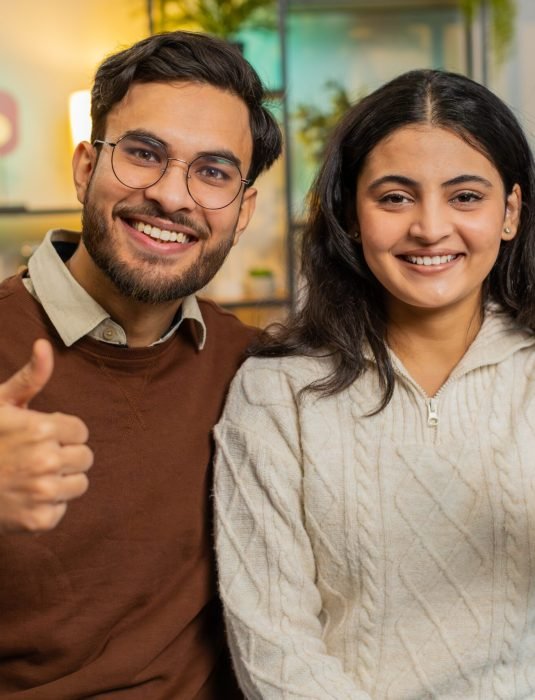 Smiling,Young,Hispanic,Couple,Sits,Arm,Around,Show,Thumbs,Up